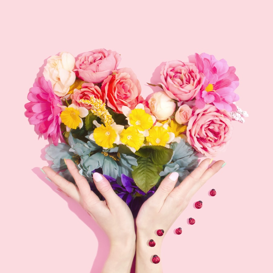Heart-shaped arrangement of pink and yellow flowers held in hands